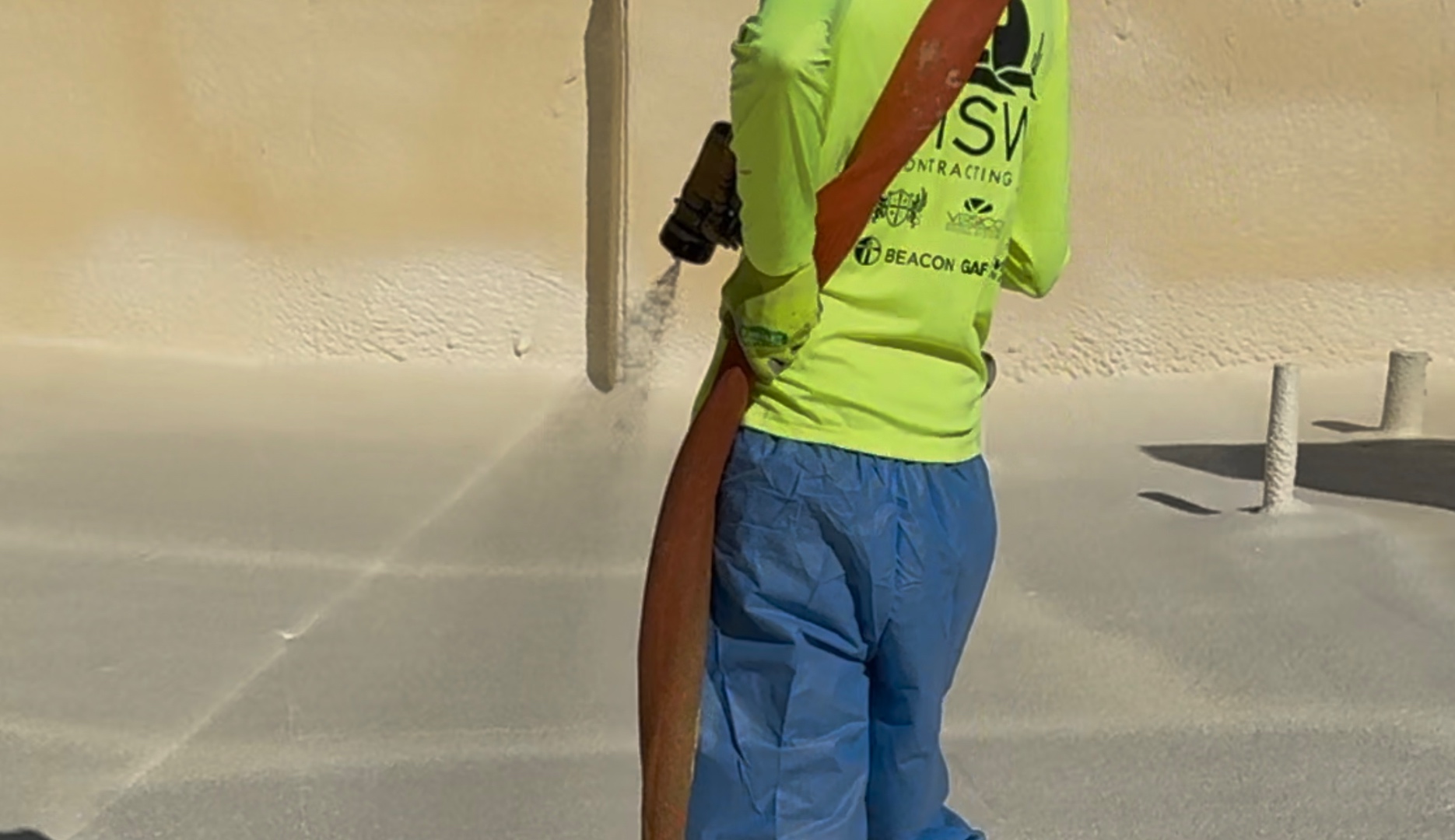 MSW Contracting crew member applying spray polyurethane foam to a commercial flat roof
