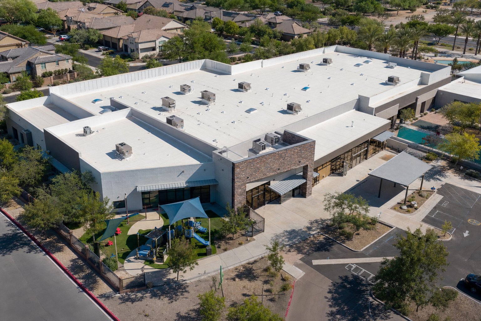 Aerial view of a Phoenix-area school and preschool building with white-coated foam roof and playground
