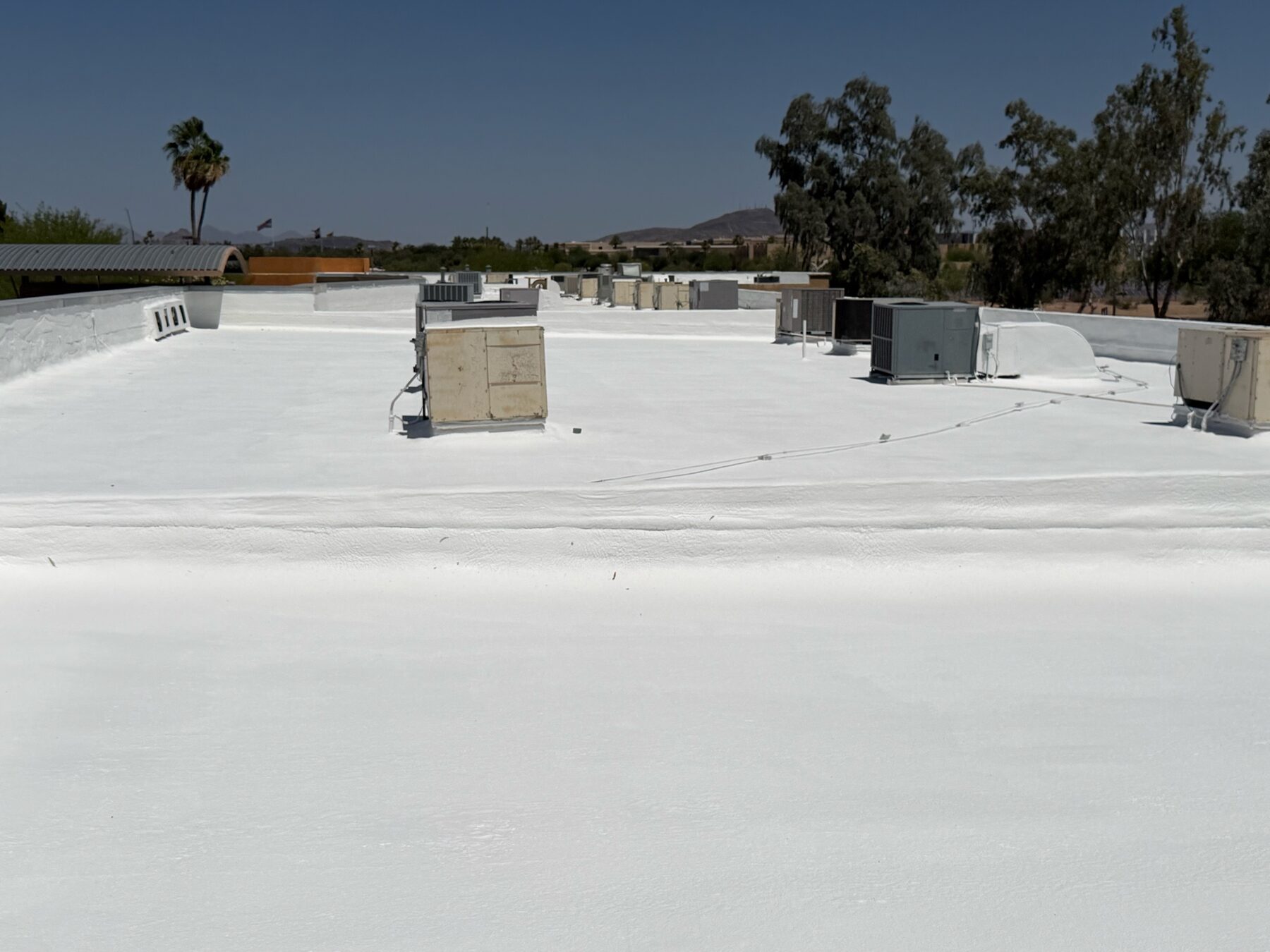 After restoration: clean reflective white ARMORCOAT AC100 elastomeric coating on the Glendale strip mall foam roof showing sealed parapet and bright finished surface