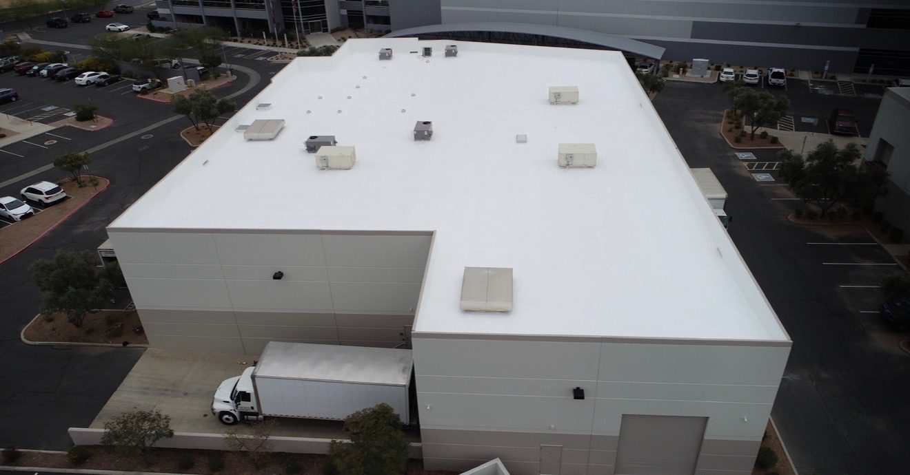 After restoration: aerial view of the completed AV Dimensions Chandler industrial foam roof showing bright reflective white AC100 elastomeric coating over prepared foam substrate with sealed HVAC curbs