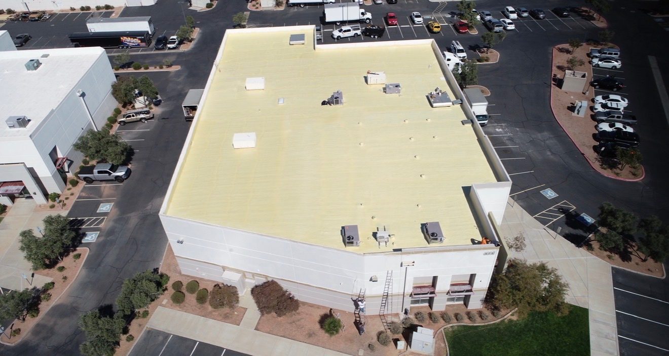 Top-down aerial drone photo of the AV Dimensions Chandler industrial roof before recoat showing weathered foam surface, HVAC curbs, vent penetrations, and skylight openings
