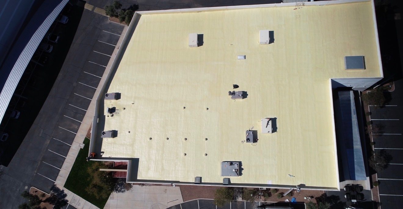 Before restoration: aerial view of the aging yellowed foam roof at AV Dimensions in Chandler AZ showing chalked and oxidized elastomeric surface with rooftop HVAC units