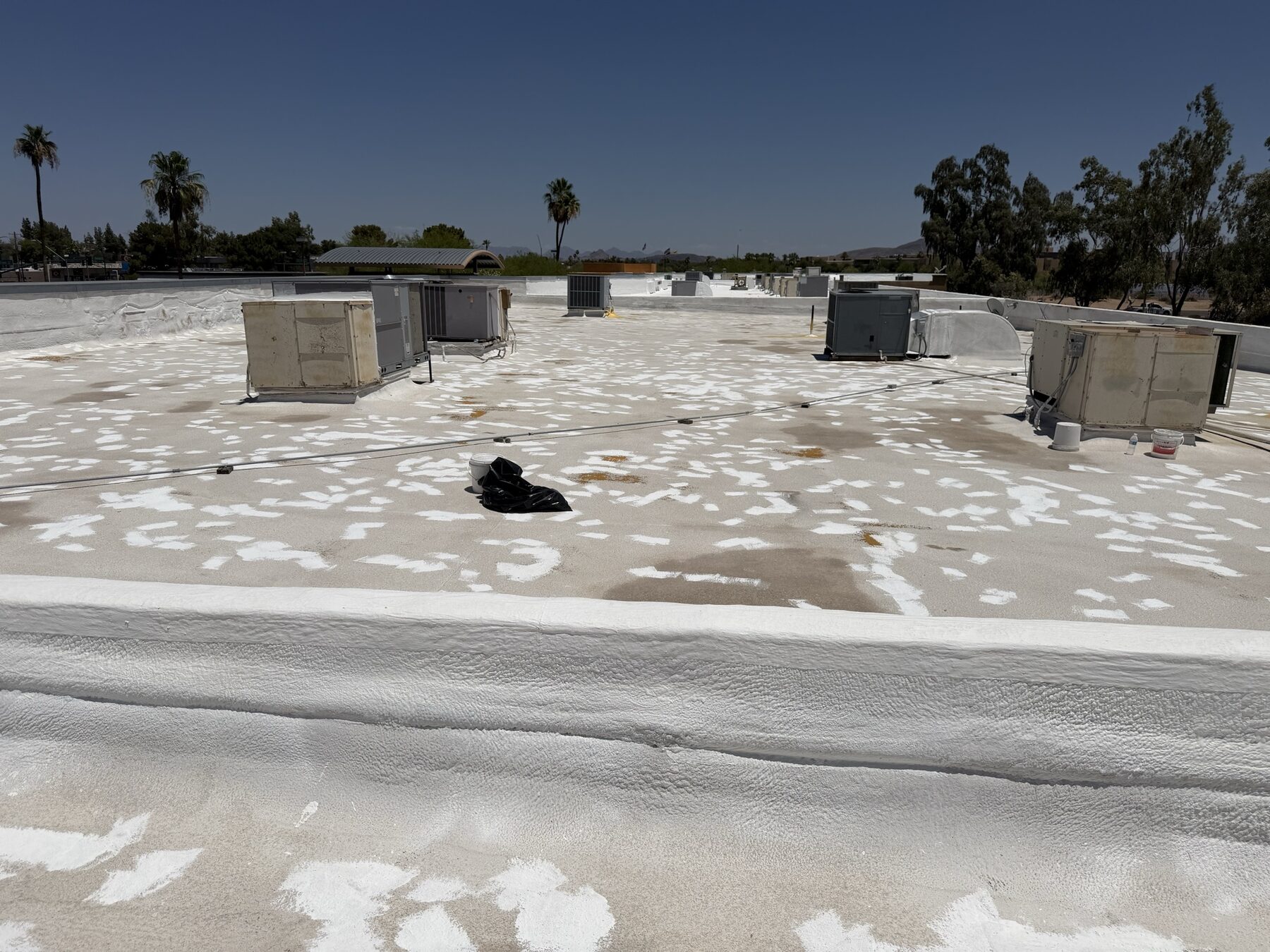 Before restoration: 20-year-old foam roof at the Glendale strip mall showing surface damage, debris, dead AC units, and decades of abandoned mechanical equipment