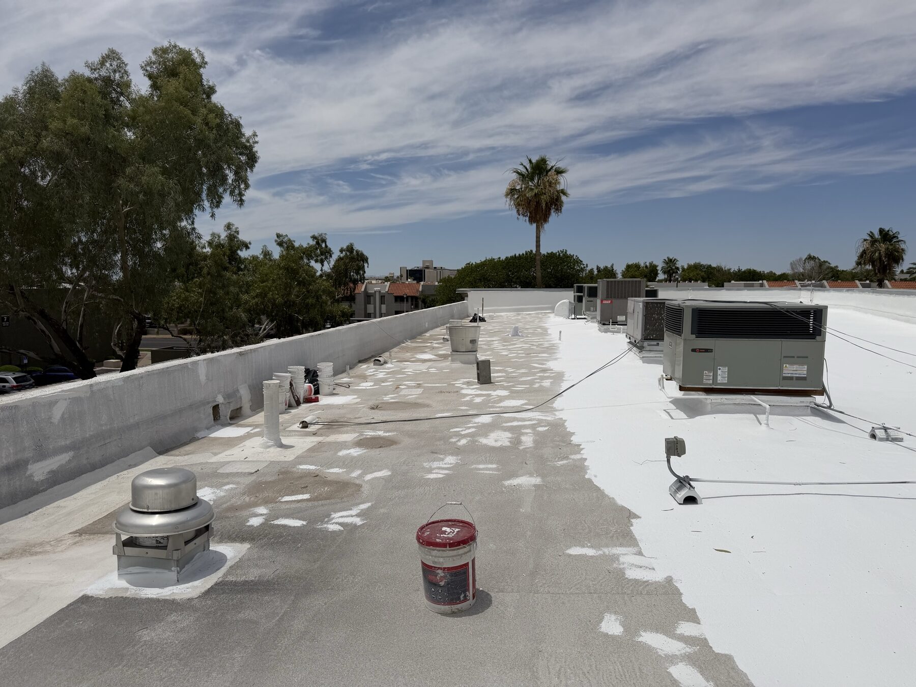 Before view of the strip mall foam roof showing dirty oxidized foam surface, unsealed vent stacks, weathered parapet, and equipment requiring repair before restoration
