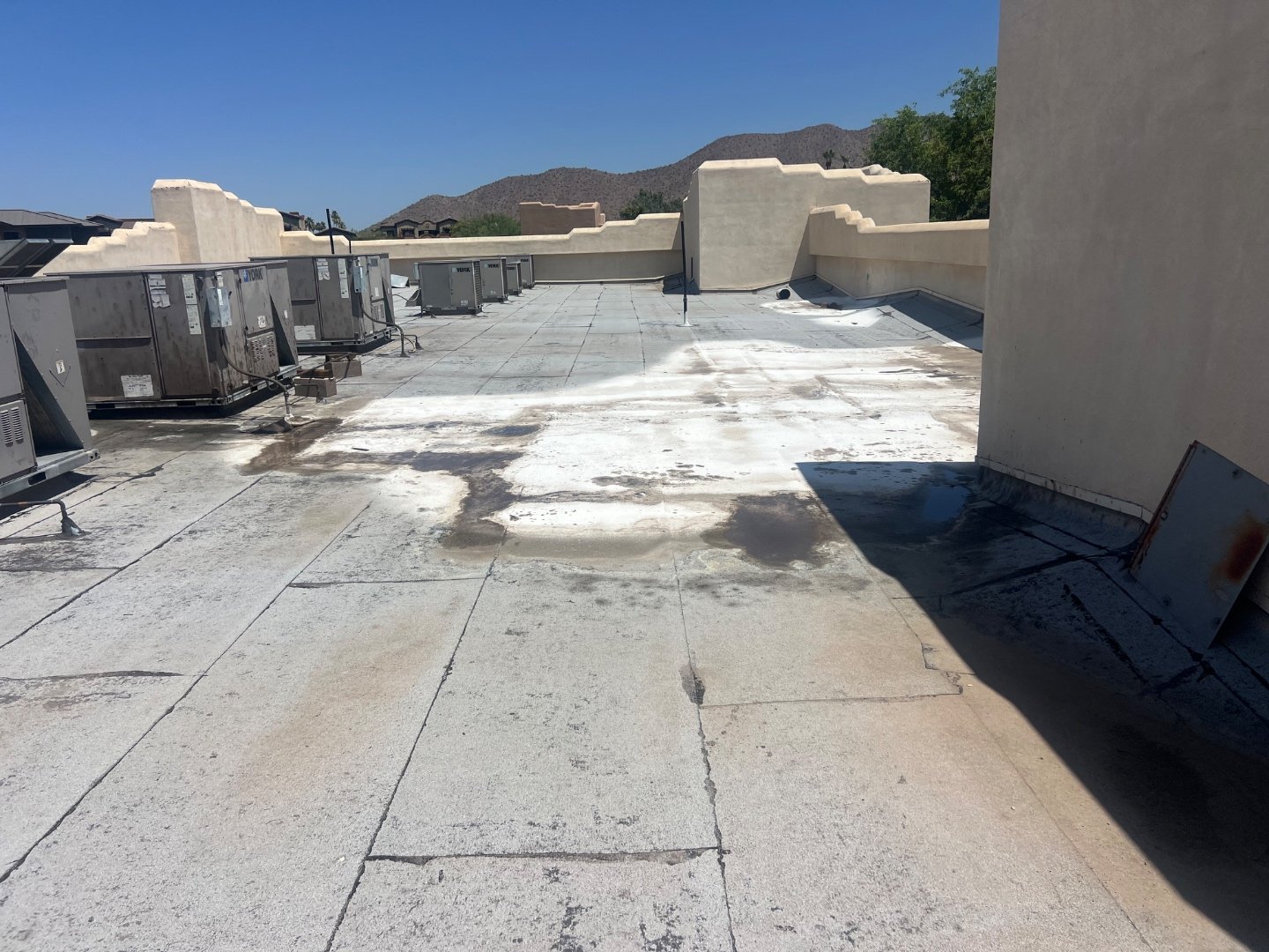 Ponding water stains on worn foam roof, McDowell Mountains and residential homes visible in background — before Vanguard Roofing restoration