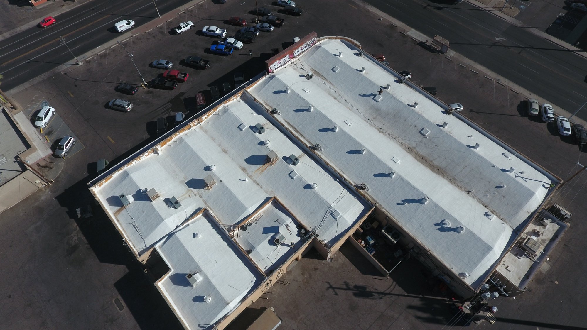 Completed 32,000 sq ft ARMORCOAT AC100 foam roof recoat at the Food City grocery store on W Van Buren St in west Phoenix — bright white finished coating with refoamed parapet walls visible from above