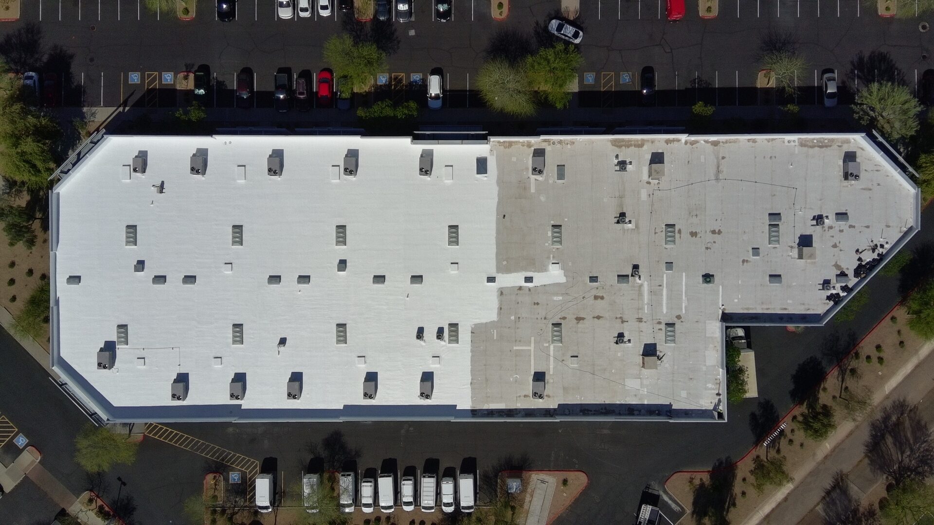Aerial drone view of 39,000 sq ft foam roof at 7427 E Hampton Ave in Mesa AZ mid-application — left side is bright white ARMORCOAT AC100 topcoat while right side still shows the aged tan foam substrate, illustrating the before-and-after transformation in a single frame