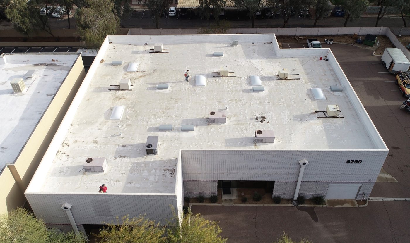 Before restoration: aerial view of the weathered polyurethane foam roof on the 9,000 sq ft Chandler industrial building showing chalked and oxidized elastomeric surface, HVAC curbs, skylights, and the building facade