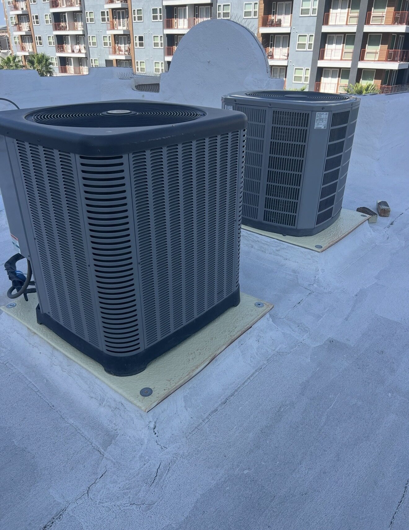 Two AC condensers on the Lofts on Fillmore HOA roof now properly mounted on new pre-foamed equipment platforms with downtown Phoenix apartments visible in the background