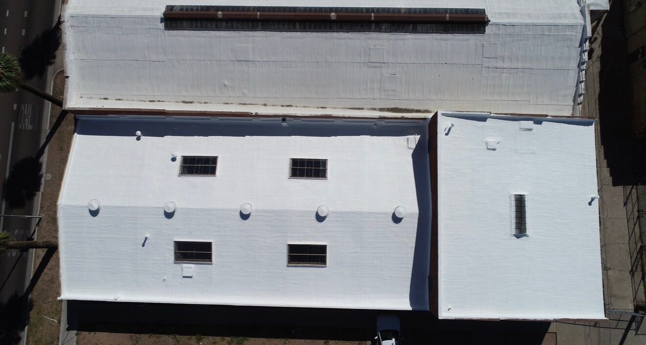 After: top-down aerial drone view of the completed PBF Manufacturing Phoenix warehouse with the new spray polyurethane foam roof, new custom-framed skylights, and sealed penetrations