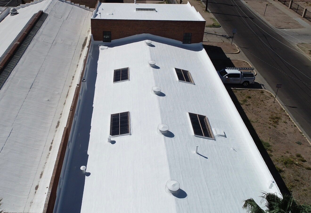 Aerial drone view of the completed 7,000 sq ft PBF Manufacturing warehouse in Phoenix AZ with a bright white new spray polyurethane foam roof and 4 new custom-framed skylights arranged in two rows of two