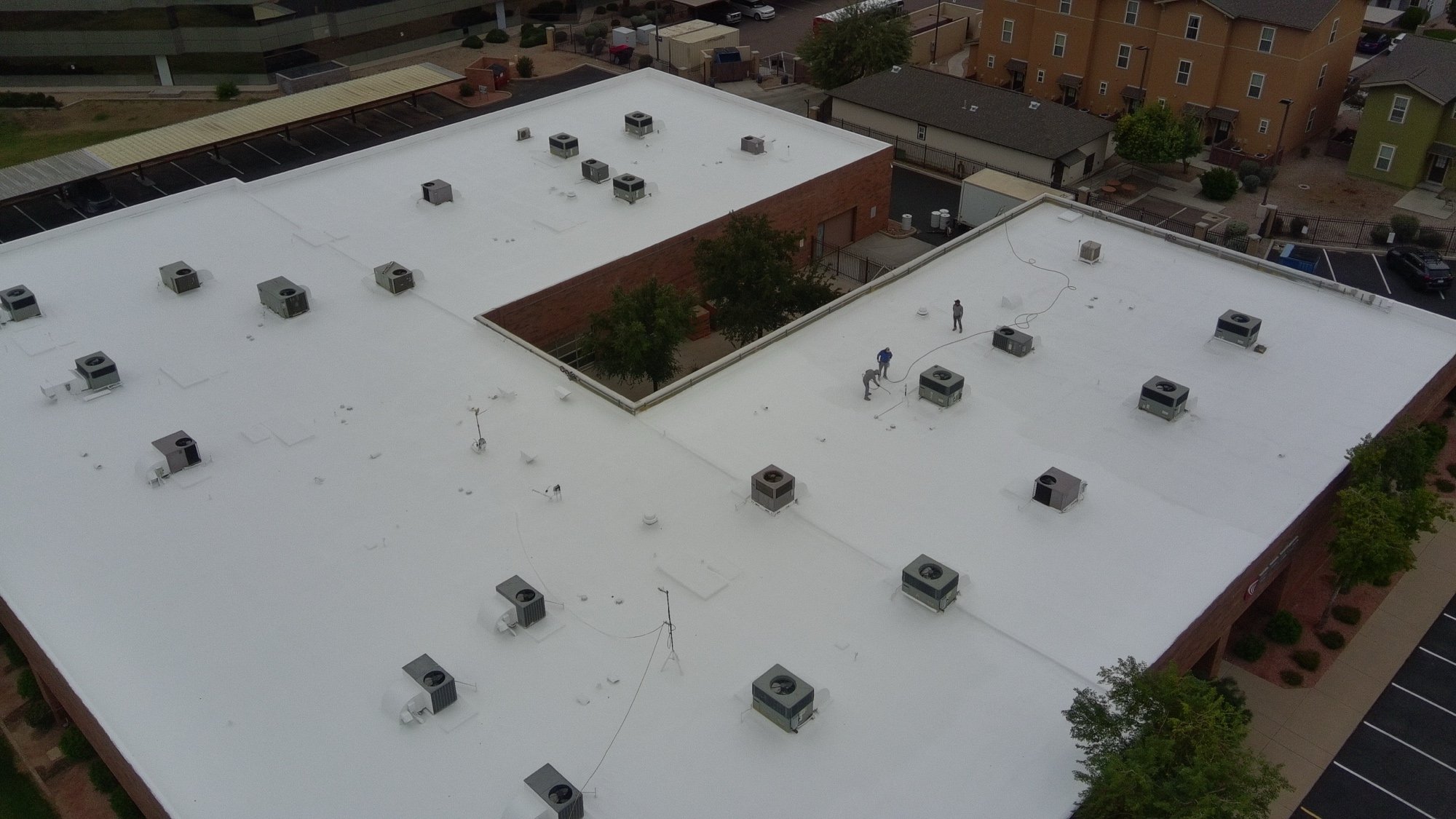 Completed 29,500 sq ft foam roof restoration at 1860 W University Dr in Tempe AZ with 523 solar panels reinstalled over the fresh white acrylic-coated polyurethane foam substrate — drone aerial view of the finished project
