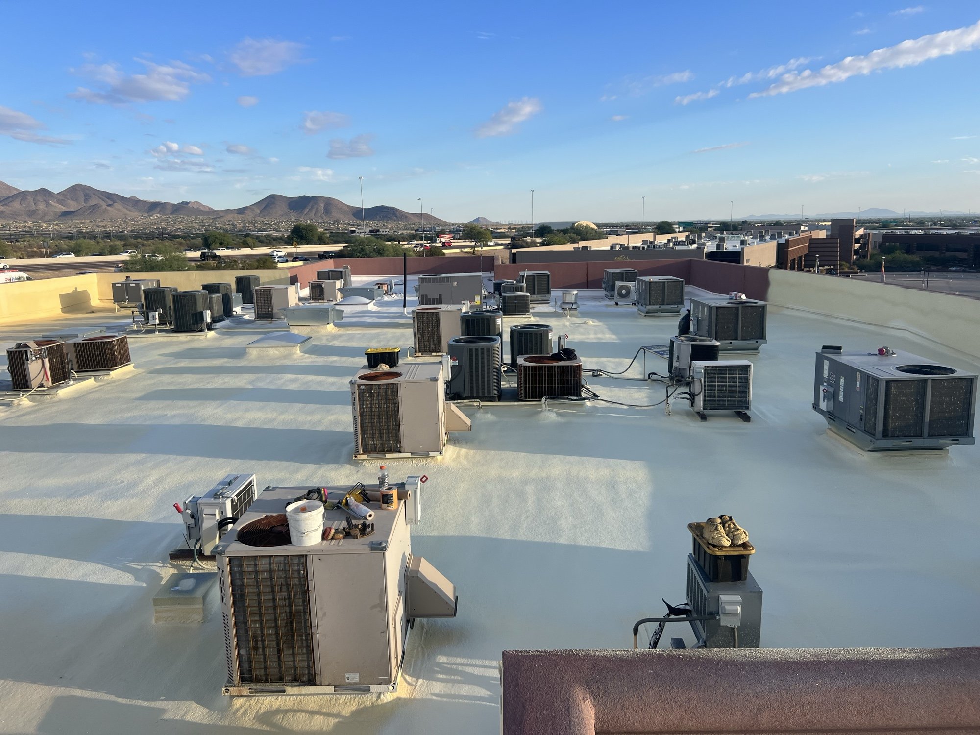 Completed 15,000 sq ft foam-over-foam recover at Venue 8600 in North Scottsdale AZ with the McDowell Mountains visible in the backdrop — fresh polyurethane foam and ARMORCOAT AC100 white finish